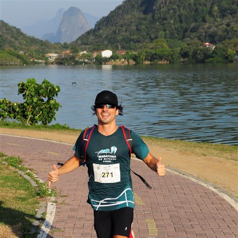 Antonio finishing a race in Niterói, thumbs up, Rio's coastline behind him.